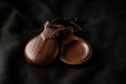 Traditional flamenco castanets resting on dark textured fabric.