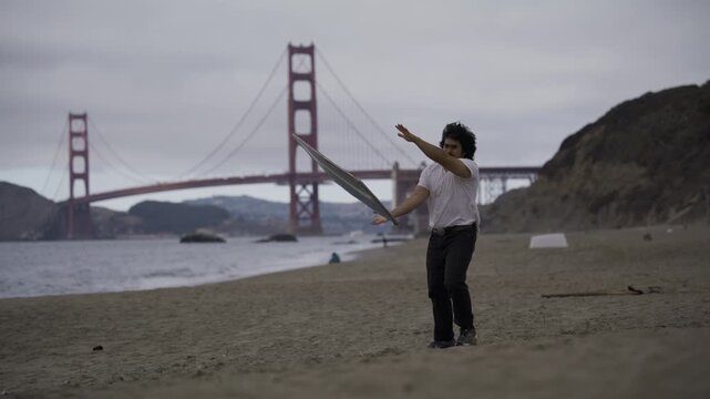 Professional Sign Spinner Near San Francisco Golden Gate Bridge Kicking Board Against The Wind And Catching It - Wide Shot