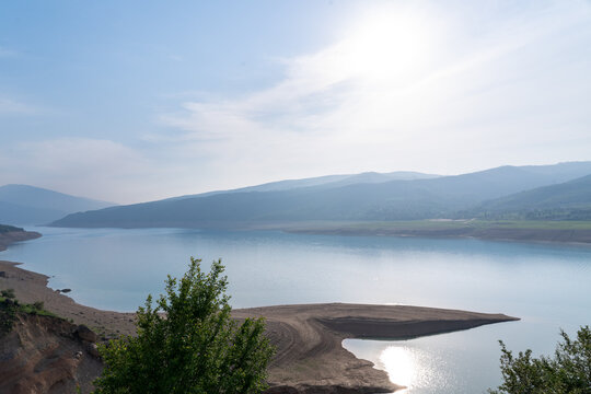 Evening view of Charvak reservoir with sun reflection on water before sunset in Uzbekistan. Concept: Central Asian nature landscape, travel, ecology