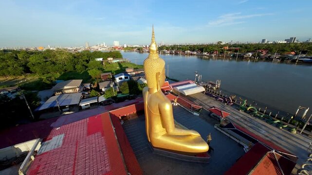 Drone view of Wat Bang Chak temple near Koh Kret Island, featuring a giant golden Buddha statue beside the Chao Phraya River in Nonthaburi, Thailand.