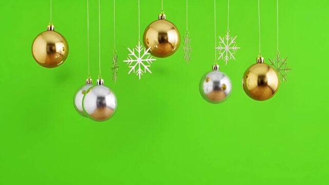 Realistic hanging gold and silver ornaments and snowflakes on green background.