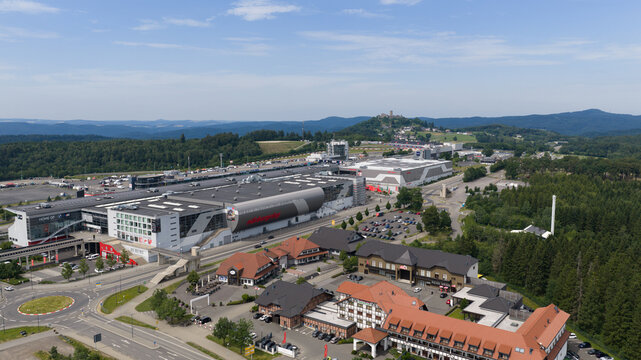 Nurburg, Germany - 23 June 2026: Aerial view of the Nurburgring Grand-Prix Strecke with its modern race track facilities, surrounding forest, and the historic Nurburg castle on the distant hill.