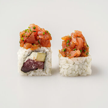 Sushi roll shown whole and cut open with tuna topping isolated on white background