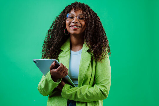 Smiling businesswoman using tablet on green background