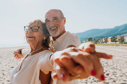 Senior couple dancing on beach enjoying a happy vacation