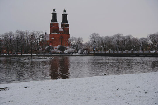 distant view of Klosters kyrka reflected on the Eskilstuna River in winter snow, Eskilstuna, Sweden.