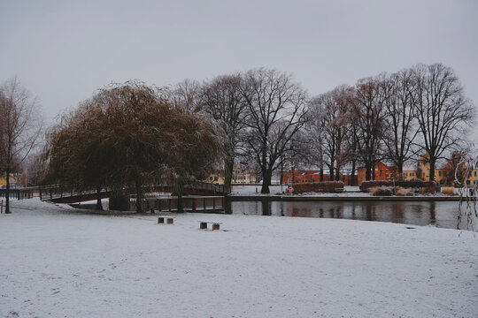 snowy park with a small bridge on the bank of the Eskilstuna River in winter, Sweden.