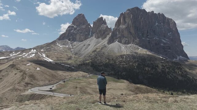 Man Standing on Mountain Ridge Overlooking Dramatic Alpine Peaks