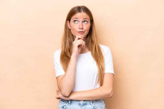 Young caucasian woman isolated on beige background thinking an idea while looking up