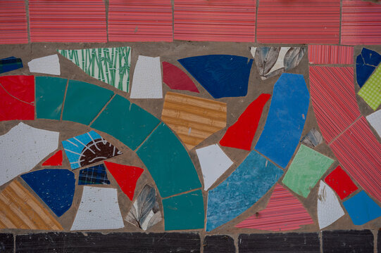 Rough concrete texture with colorful ceramic mosaic made of tile pieces