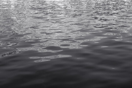 Abstract reflections on rippled water surface in black and white. Background with abstract natural shapes, copy space.