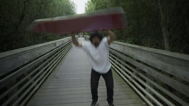 Man Carrying Painted Board And Doing Epic Tricks on Wooden Boardwalk
