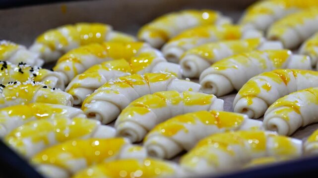 Hands Sprinkling Sesame Seeds and Spices on Homemade Bread Rolls in Baking Tray Before Baking