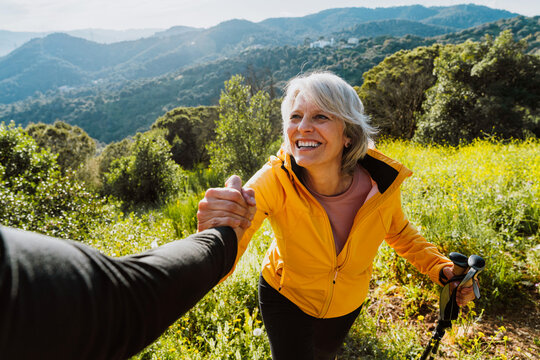 Older woman receiving helping hand while hiking outdoors