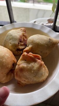 Close up of Bengali singara (shingara), a crispy triangular fried pastry filled with spiced potatoes, cauliflower, and peanuts. Popular snack in Bangladesh and India.