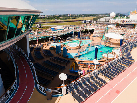Riga, Latvia - 09 June 2022: Aerial view of the upper deck of a cruise ship featuring swimming pools, lounge chairs, and a running track.