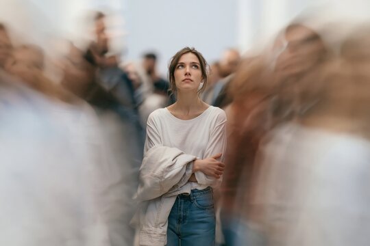 Woman with wavy hair standing calmly in a crowded space