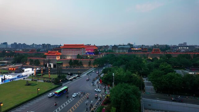 An elevated view of an urban area featuring ancient city walls, dense green parks, and multi-lane busy roads with vehicles. 