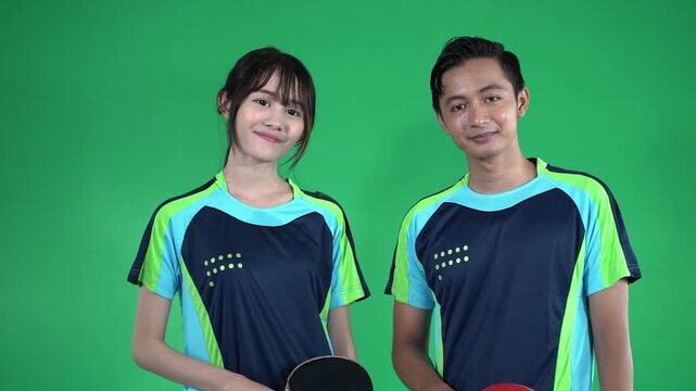 Near-start to near-end sequence shows two young table tennis players shifting from side profile to front-facing pose, smiling in green studio with paddle