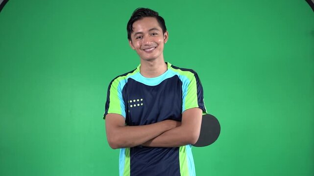 Young table tennis player in green studio moves from focused serve preparation to relaxed smiling pose, holding paddle and facing camera under even lighting