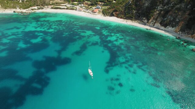 Sailboat anchored in turquoise water near sandy beach Petani of Kefalonia Greece