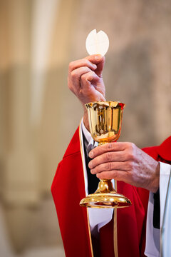 Catholic priest elevating the Eucharistic host above golden chalice during Holy Mass, symbolizing faith, consecration and Christian worship
