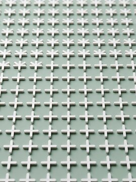 Minimalist Pattern of White Plastic Tile Spacers on a Green Background