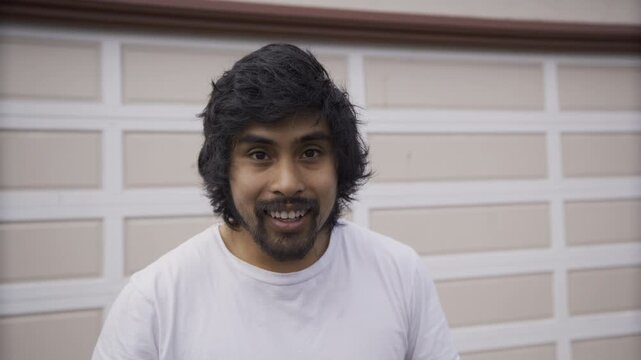 Young Man Smiling For Camera In Front Of Garage - Slow, Steady Cam Shot