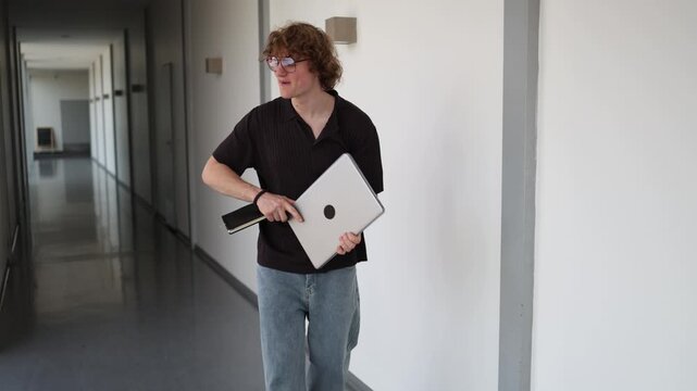 Vertical screen young startup founder walking with laptop and notebook celebrating business success while checking results feeling excited inspired and confident
