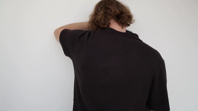 Vertical screen young man leaning against a wall after failing university admission showing disappointment frustration academic setback uncertainty and stress