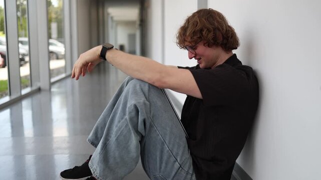 Sad student sits alone in the school hallway feeling rejected after classmates exclude him showing loneliness emotional stress social isolation and bullying