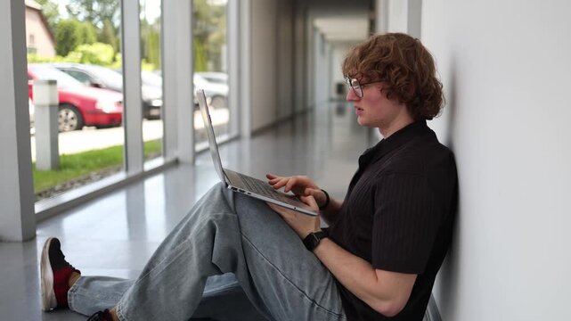 Young entrepreneur sits on the office floor after a business setback feeling lost and overwhelmed searching for solutions after a failed startup decision