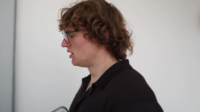 Young job applicant walks through office corridor feeling nervous before interview holding laptop with anxious expression showing career stress and uncertainty