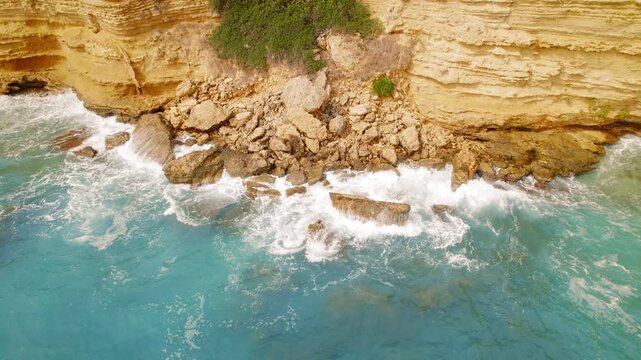 Coastal rockfall scene where cliff meets turquoise sea in summer Greece