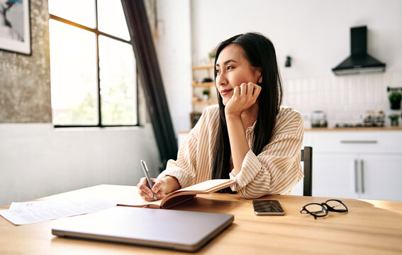Woman writing in notebook at home.