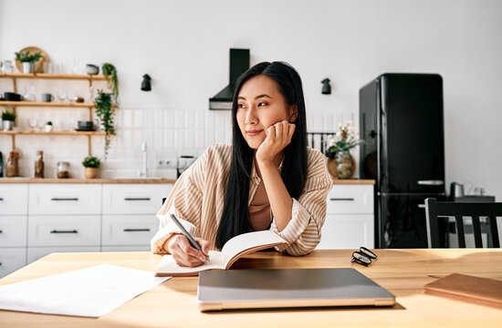 Young woman writing in a modern home kitchen.