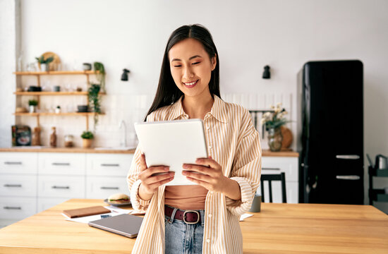 Young woman using tablet in modern kitchen.