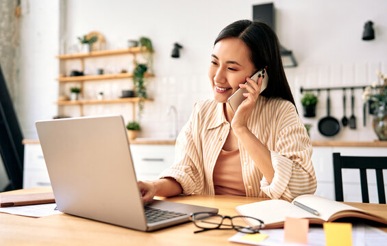 Young woman talking on phone while working at home.