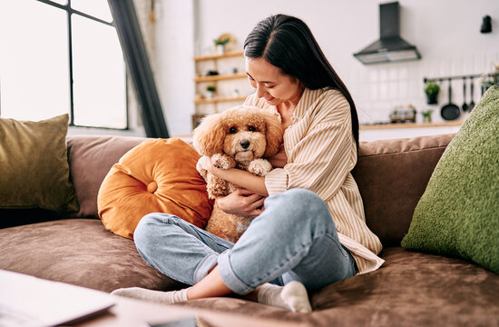 Woman hugging pet on a sofa at home.
