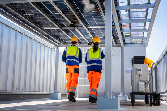 Solar power technicians inspecting rooftop solar panel installation, Renewable energy team working on industrial solar rooftop array, Professional engineer performing maintenance on solar power system