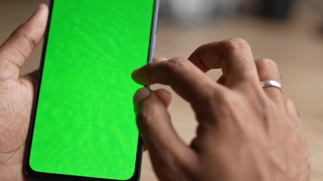 A user interacts with a smartphone showcasing a vibrant green screen in both frames, demonstrating tactile engagement and user interface potential.