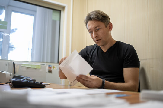 Surprised office worker reading a document with an open mouth. Unexpected news, shock, or surprising business letter.