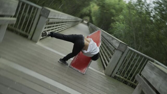 Man Doing Cool Cart-Wheel And Spinning Large Sign On Wooden Boardwalk - Slow Motion Tilt Shot