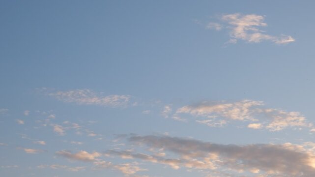 Evening sky in soft blue tones with clouds tinged in delicate pink hues. Gentle flutter of birds or insects. Peaceful transition from day to night. Nature, twilight, summer evenings, landscape