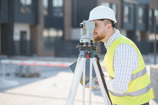 Land surveyor engineer using total station at construction site