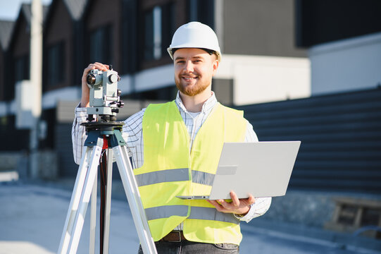 Young surveyor using a theodolite and laptop on construction site
