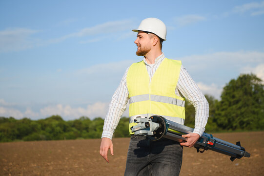 Surveyor holding leveling instrument preparing for land measurement