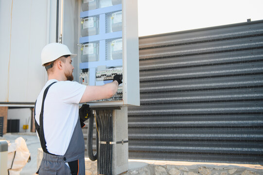 Electrician performing maintenance on outdoor electrical panel