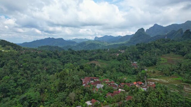 Aerial drone footage of Besuki village in the middle of a valley, in Wadaslintang area, Wonosobo regency, Java island area, Indonesia, with forest and moutains around
