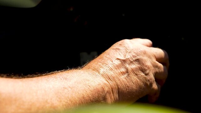 Elderly hand on a manual gear shift.